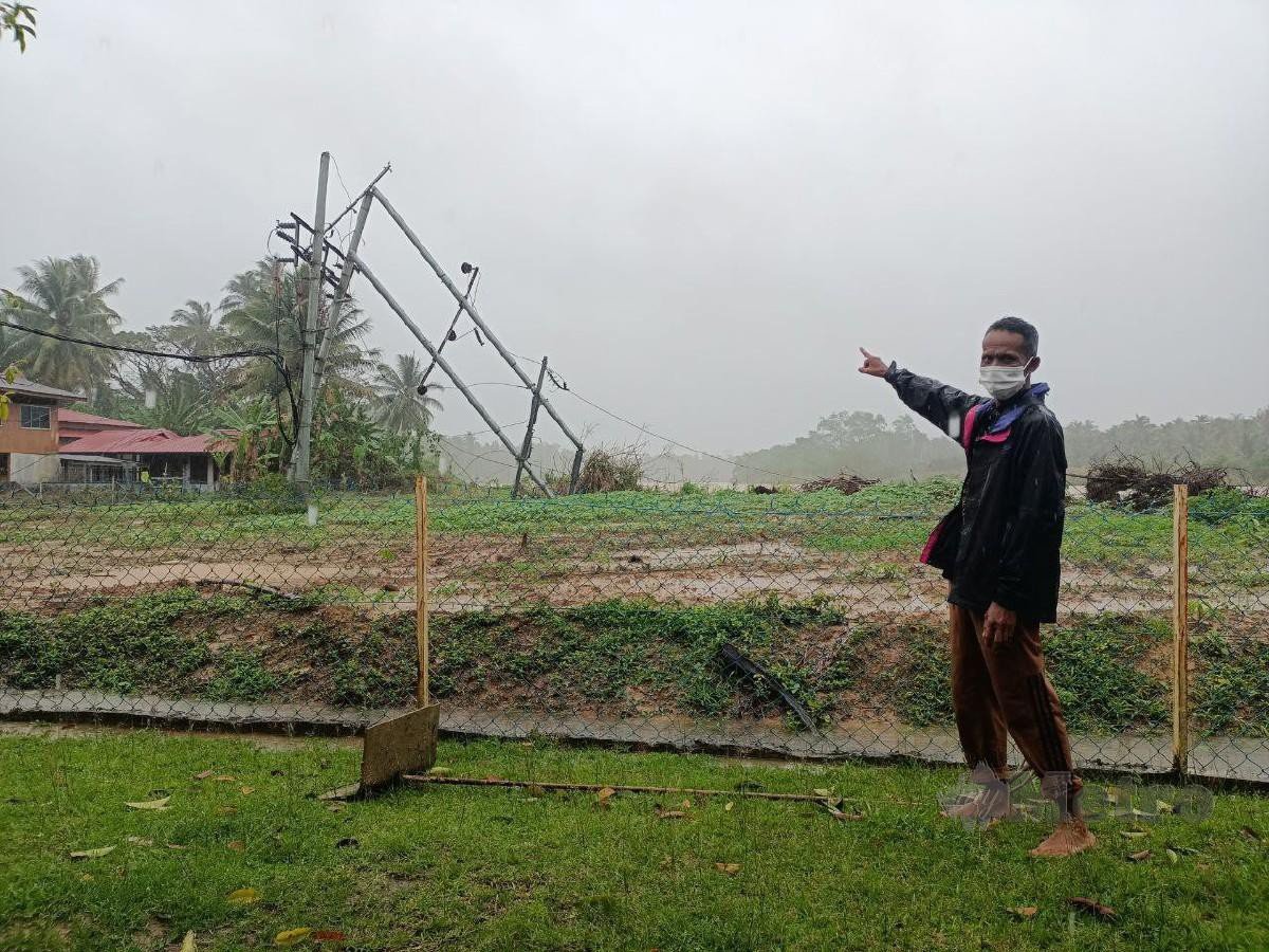 CHE Dir menunjukkan tiang kabel elektrik di Kampung Pulau Beluru yang tumbang dirempuh kapal pengorek pasir. FOTO Siti Rohana Idris
