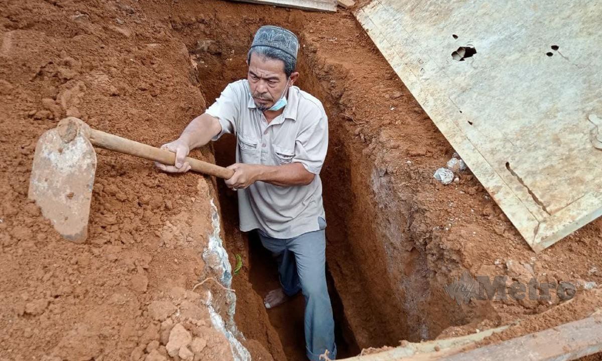 Najib menggali kubur buat persiapan pengkebumian kariah di Tanah Wakaf Perkuburan Islam di Kampung Berata di sini. FOTO AHMAD ISMAIL