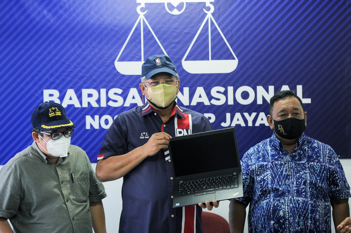 ANNUAR (tengah) menunjukkan komputer riba yang disumbangkan kepada petugas BN sepanjang PRN Melaka. FOTO Bernama