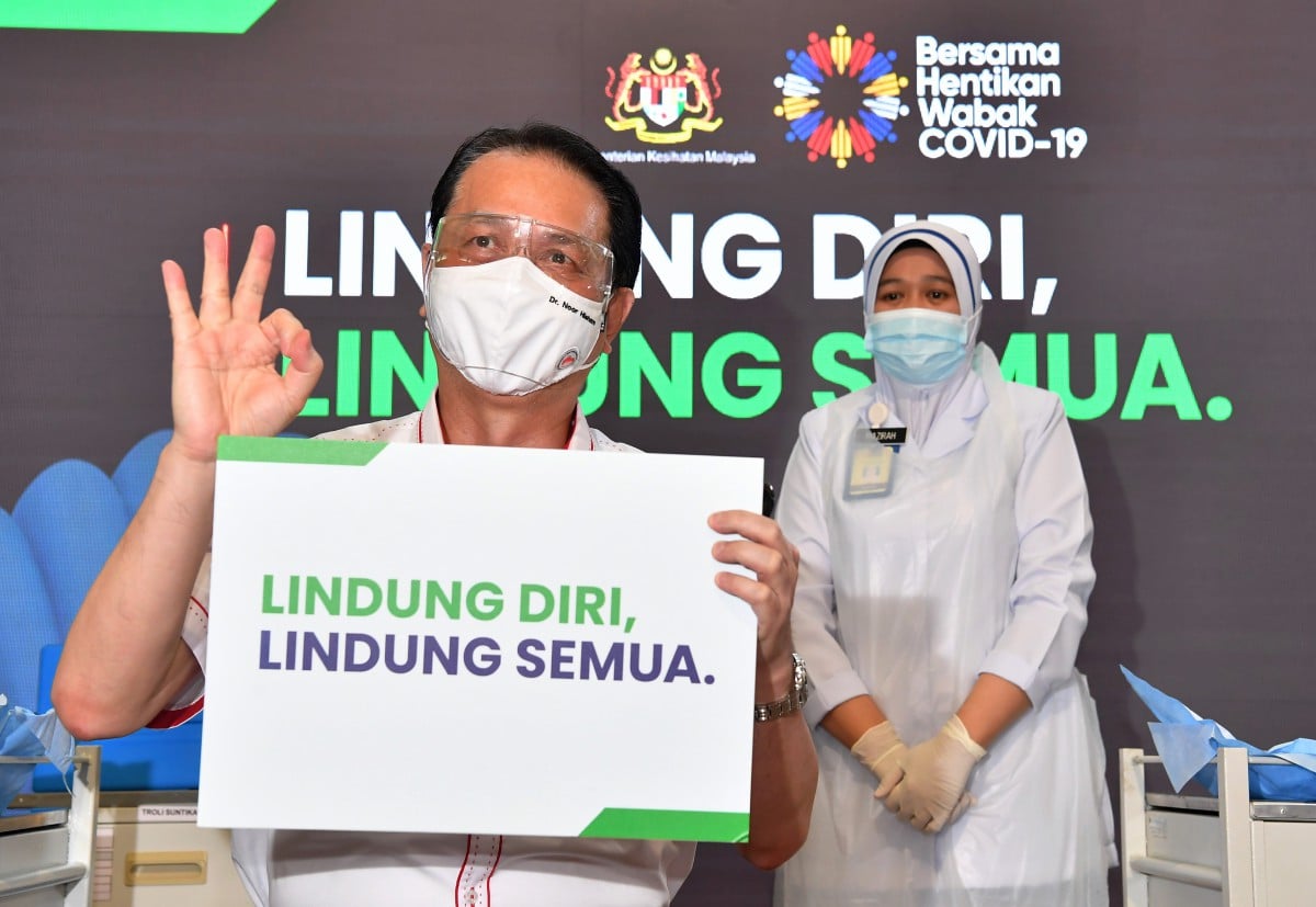 DR Noor Hisham menunjukkan playcard 'Lindungi Diri, Lindungi Semua’ selepas disuntik vaksin Pfizer-BioNTech di Pusat Kesihatan Daerah Putrajaya. FOTO Bernama 