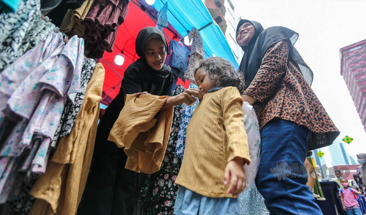 SEORANG kanak-kanak mencuba baju raya. FOTO Aswadi Alias