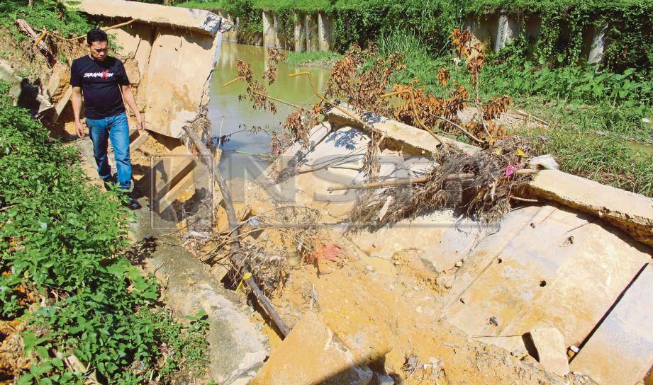 NORIZAN menunjukkan keadaan tebing konkrit yang runtuh akibat hujan lebat berterusan berhampiran kawasan perumahan Taman Desajaya, Seremban. FOTO Adzlan Sidek. 