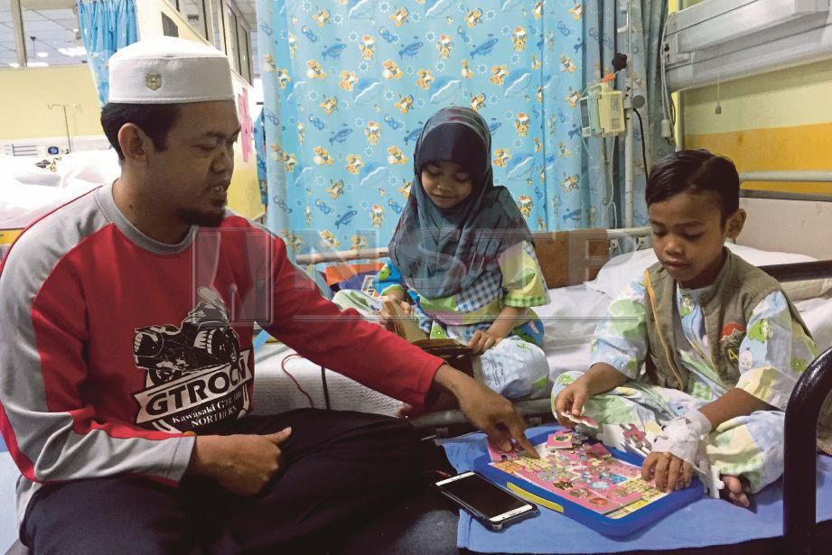 MUHAMAD Solihin Zakaria menjaga anaknya, Nur Tasnim, 9, (tengah) dan Muhammad Mush’ab Umair, 8, yang menerima rawatan di Wad Pediatrik Hospital Canselor Tuanku Muhriz (HCTM), Cheras, hari ini. FOTO Zulfadhli Zulkifli