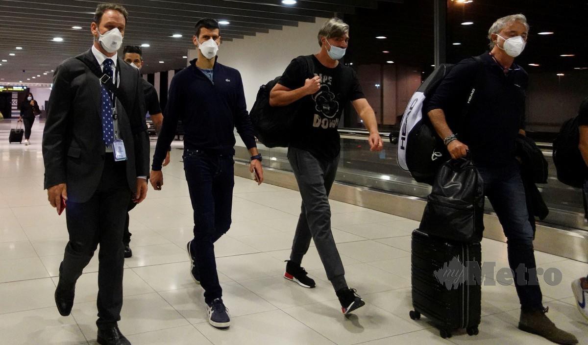DJOKOVIC berjalan bersama pasukannya menuju ke kapal terbang di Lapangan Terbang Melbourne selepas diusir dari Australia. FOTO Reuters