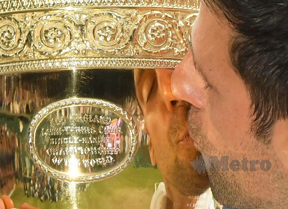 DJOKOVIC mencium trofi Wimbledon. - FOTO Reuters 