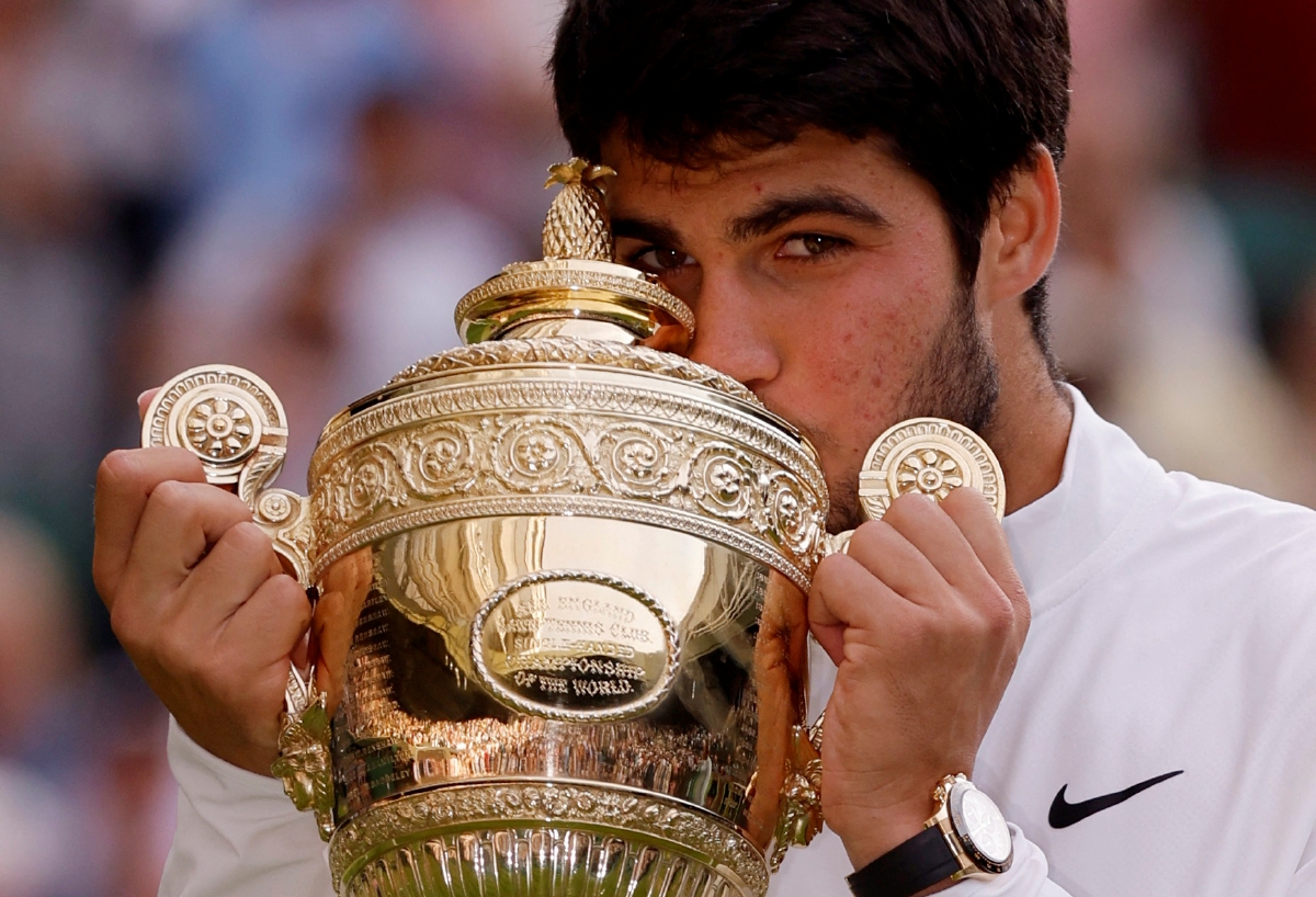 ALCARAZ mengucup trofi selepas muncul juara Wimbledon. FOTO REUTERS 