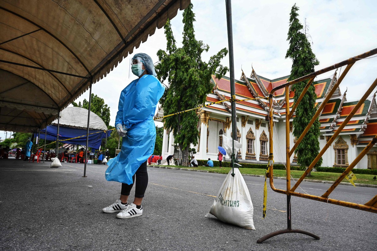PEKERJA kesihatan membantu penduduk melakukan ujian saringan Covid-19 di Kuil Wat Phra Sri Mahatat Buddhist di Bangkok, semalam. FOTO  AFP
