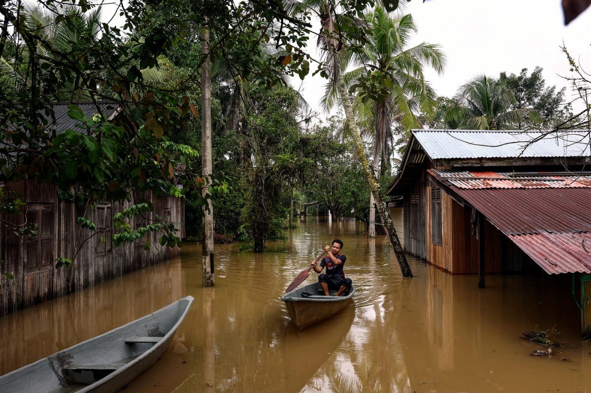 PENDUDUK mendayung sampan untuk keluar dari kediamannya yang digenangi air di Kampung Kubang Gual hari ini.FOTO Bernama 