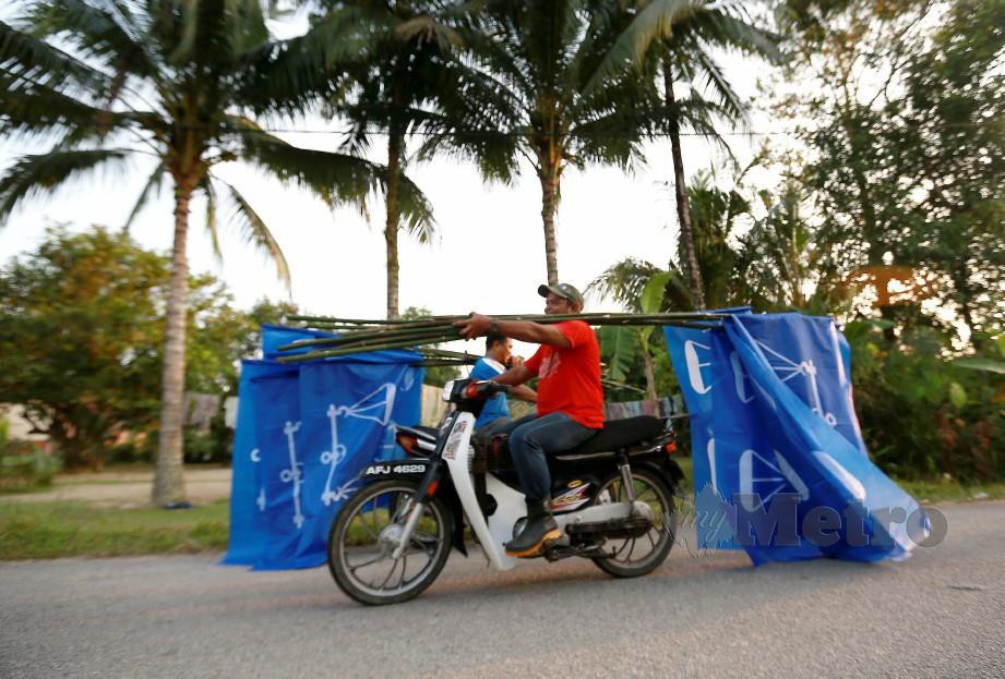 Penyokong BN menunggang motosikal sambil membawa bendera untuk di pasang di sekitar Kampung Klah sempena PRK DUN Slim. Foto Sharul Hafiz Zam 