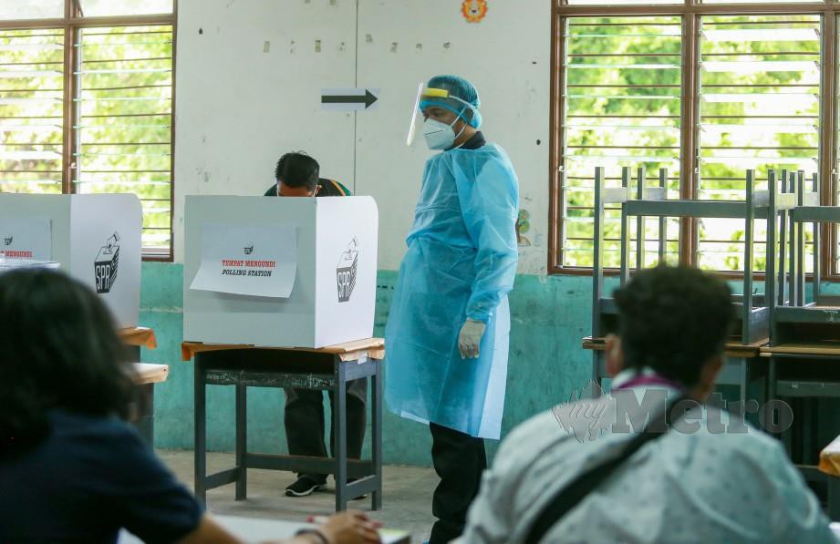 PETUGAS Kementerian Kesihatan memakai PPE memantau proses pengundian supaya patuh SOP di pusat mengundi Sekolah Kebangsaan Sembulan. FOTO Aswadi Alias.