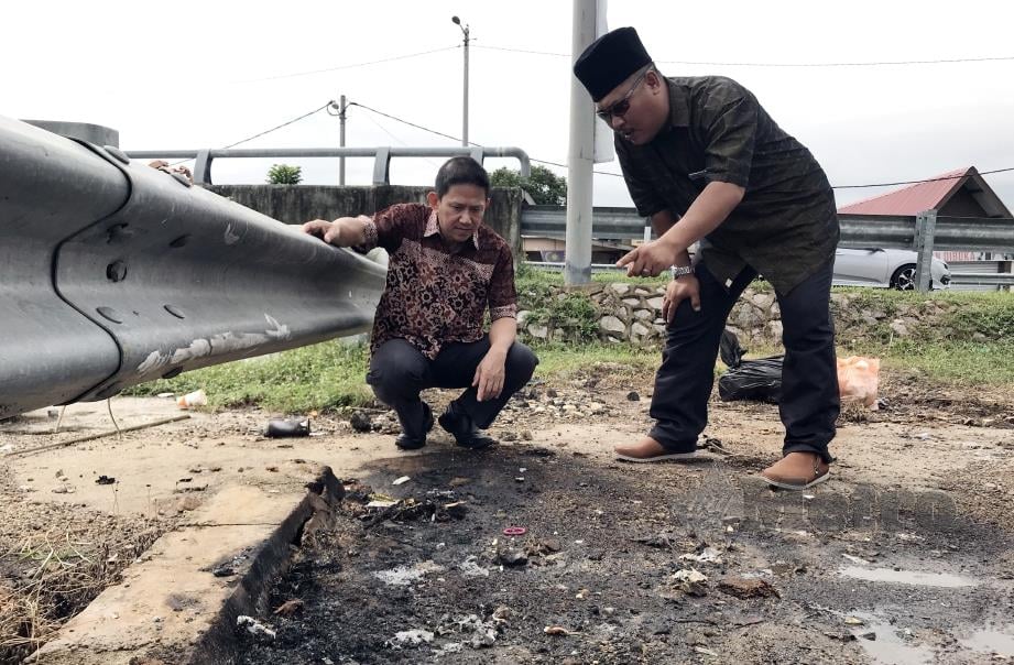 GUE (kiri) bersama Amer melihat kesan terbakar selepas tong sampah dibakar di Jalan Kampung Tengah, Tanjung Minyak, Bukit Rambai, Melaka. FOTO Rasul Azli Samad. 
