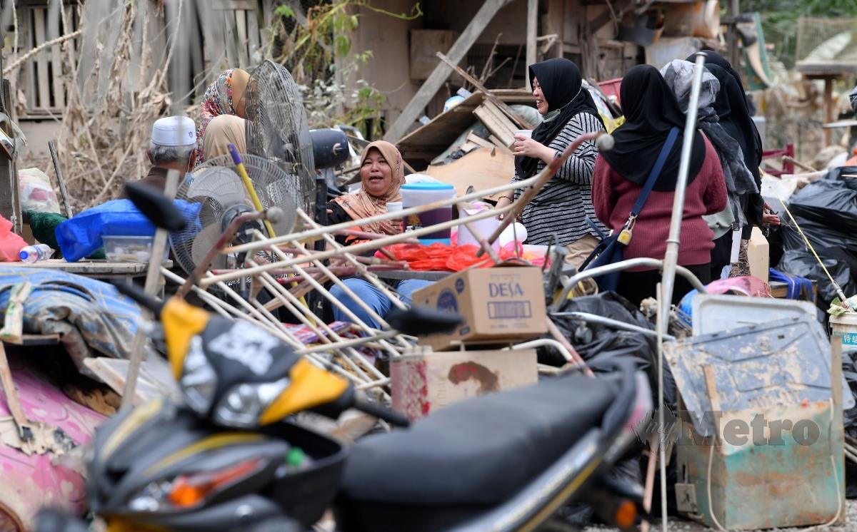 Mangsa banjir di Kampung Sri Tanjung berehat seketika dicelah-celah timbunan barangan rosak ketika tinjauan fotoBernama di Kampung Sri Tanjung Dengkil hari ini. FOTO BERNAMA