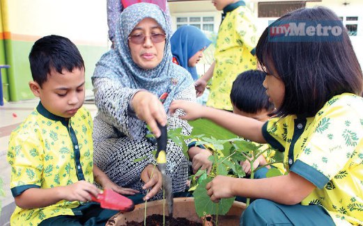 NOOR HAYATI menunjukkan cara menanam pokok bendi kepada si kecil. 