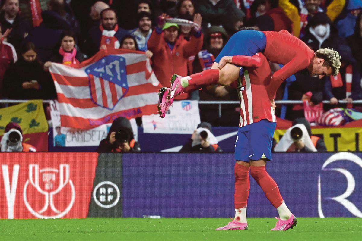 GRIEZMANN diangkat pemain pertahanan Atletico Madrid, Jose Gimenez selepas menjaringkan gol ketiga mereka. FOTO AFP 
