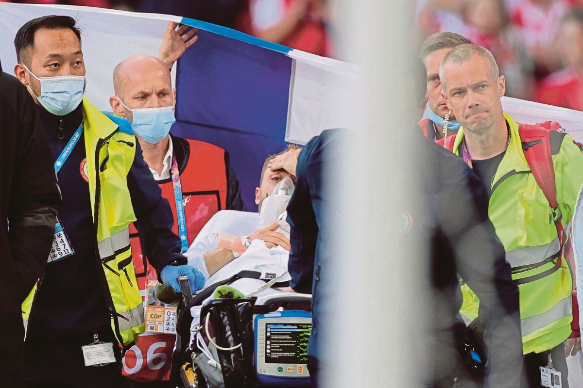TOPSHOT - Denmark's midfielder Christian Eriksen (C) is evacuated after collapsing on the pitch during the UEFA EURO 2020 Group B football match between Denmark and Finland at the Parken Stadium in Copenhagen on June 12, 2021. (Photo by Friedemann Vogel / various sources / AFP)