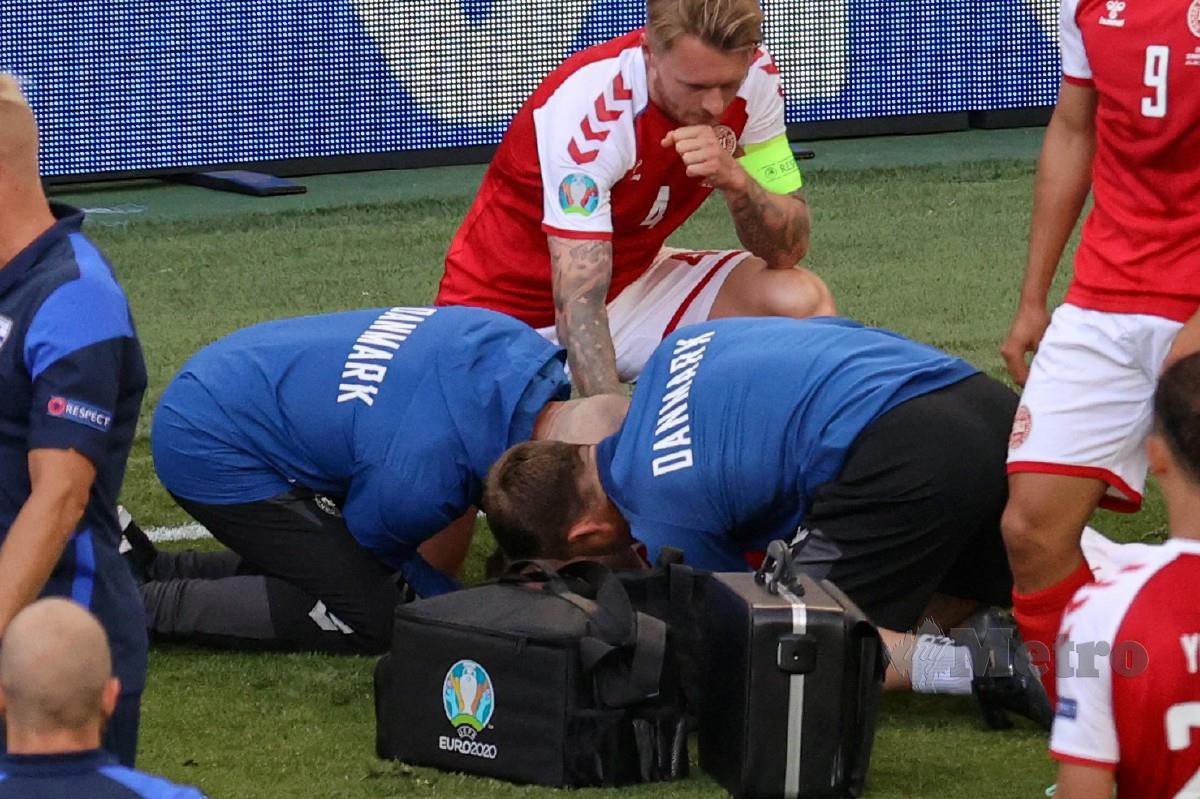 KJAER (tengah) kekal di sisi Eriksen ketika pasukan perubatan merawat rakan sepasukannya itu. FOTO AFP