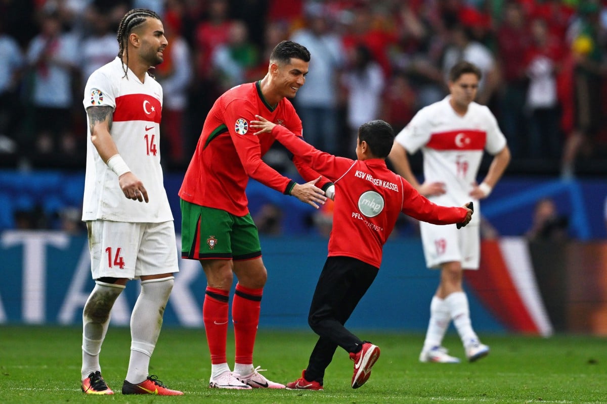 SEORANG kanak-kanak berjaya mencerobohi padang untuk bergambar dengan Ronaldo. -FOTO AFP 