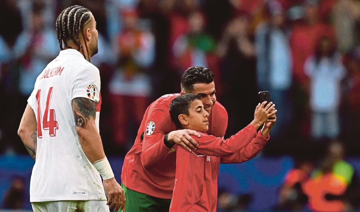 KANAK-KANAK lelaki menceroboh padang  untuk berswafito dengan Ronaldo. FOTO AFP 