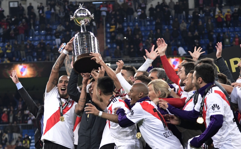 PEMAIN River Plate menjulang trofi Copa Libertadores selepas membenam Boca Juniors 3-1 pada aksi final yang terpaksa dipindahkan lebih 10,000 kilometer dari Argentina. FOTO AFP