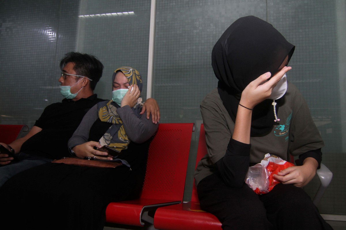 AHLI keluarga berkumpul di Lapangan Terbang Supadio, Kalimantan Barat. FOTO AFP