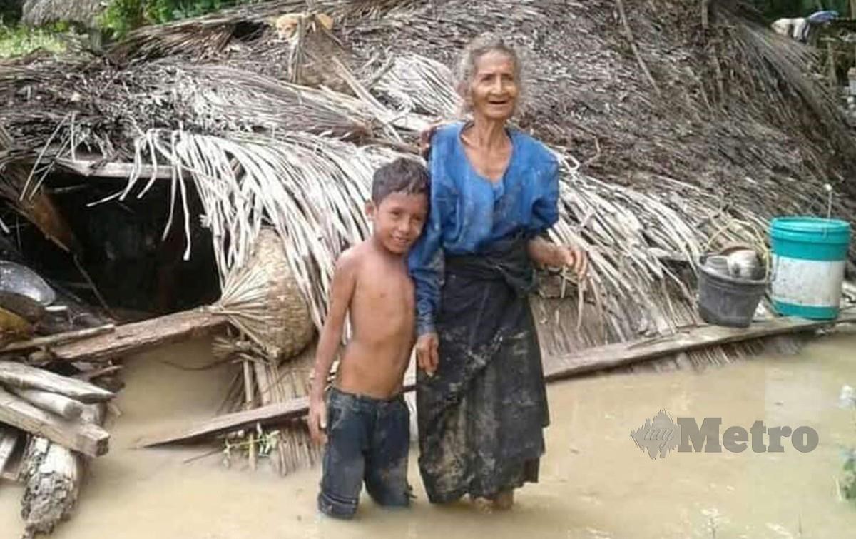 Warga emas bersama cucunya yang meninjau keadaan rumah mereka musnah akibat tanah runtuh dan banjir kilat di Flores. FOTO AFP
