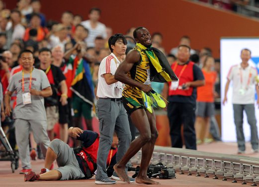 Bolt dibantu seorang kakitangan trek selepas dilanggar jurukamera televisyen. - PIX AFP