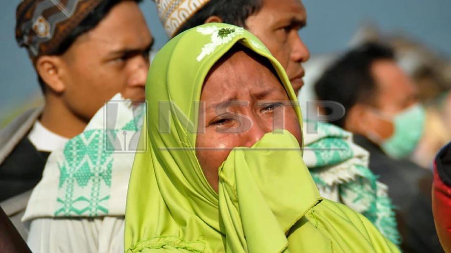 Wanita menangis melihat nasib penduduk serta kerosakan dialami akibat tsunami. FOTO AFP 
