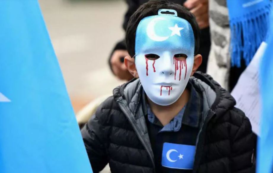 BUDAK lelaki memakai topeng muka ketika demosntrasi membantah penindasan etnik Muslim Uighur, pada 2018. FOTO AFP  