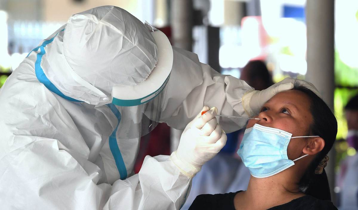 KAKITANGAN Kementerian Kesihatan mengambil sampel dari hidung seorang penduduk Taman Mawar, Sandakan. FOTO BERNAMA
