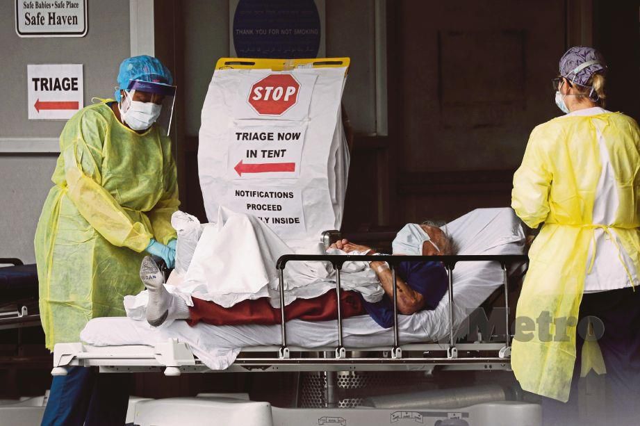PETUGAS kesihatan membantu membawa pesakit Covid-19 ke hospital di New York. FOTO AFP