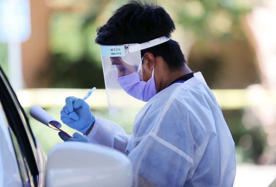 PETUGAS kesihatan melakukan ujian saringan pandu lalu Covid-19 di Los Angeles. FOTO AFP 