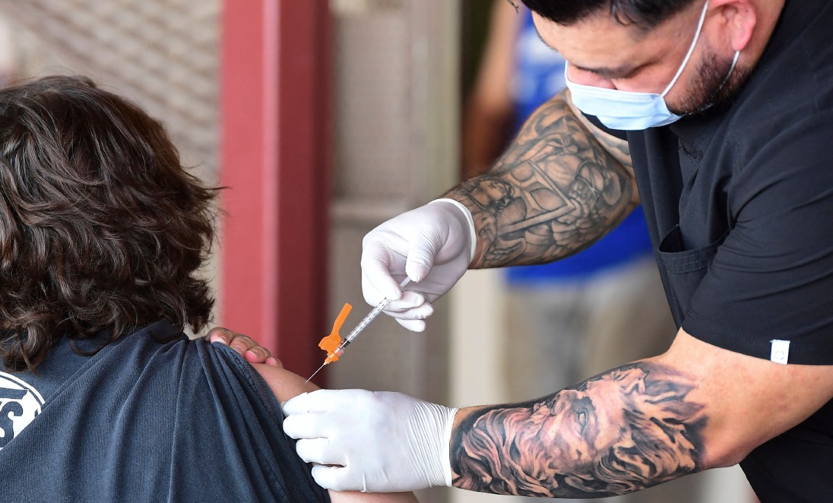 Petugas kesihatan menyuntik vaksin kepada penerima. FOTO AFP