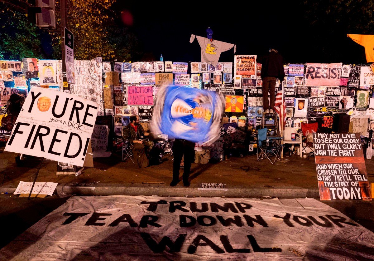 PELUKIS memaparkan karya dengan imej Donald Trump berhampiran Rumah Putih. FOTO AFP 