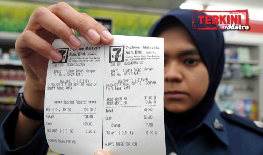 PENGUAT kuasa Jabatan Kastam Diraja Malaysia Bahagian GST, Wan Azlinda Osman memegang dua resit bayaran perkhidmatan telefon mudah alih pra-bayar yang menunjukkan kaedah catatan Cukai Barangan dan Perkhidmatan (GST) yang berbeza semasa Ops GST yang dilaksanakan bersama JKDM dan KPDNKK Perlis. FOTO Hafizudin Mohd Safar