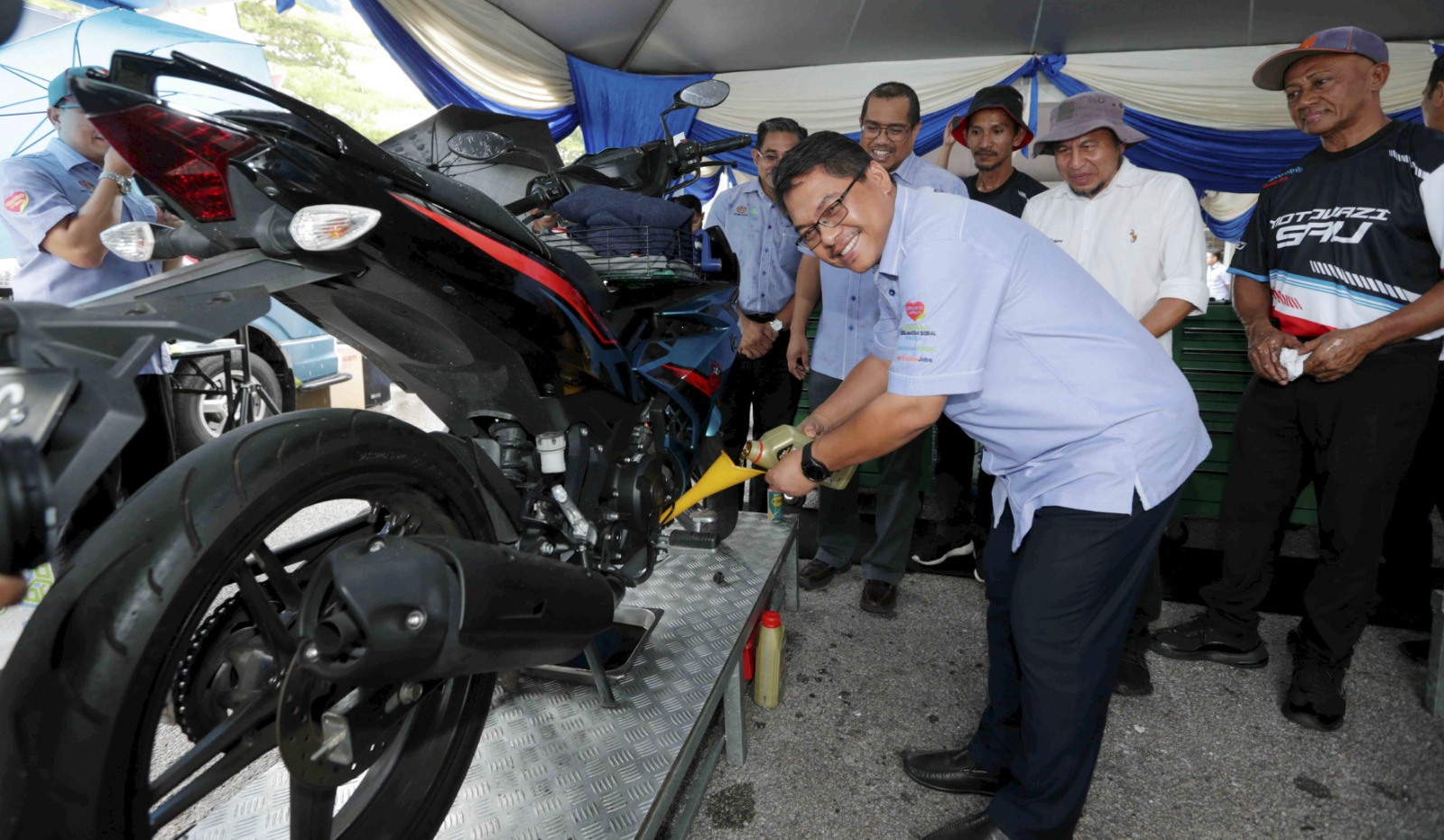 MUSTAPHA menukar minyak enjin sebuah motosikal pada Program Advokasi Pencegahan Kemalangan dan Promosi Kesihatan Perkeso
2023 di Lotus Stargate Sungai Petani. - FOTO Syaharim Abidin