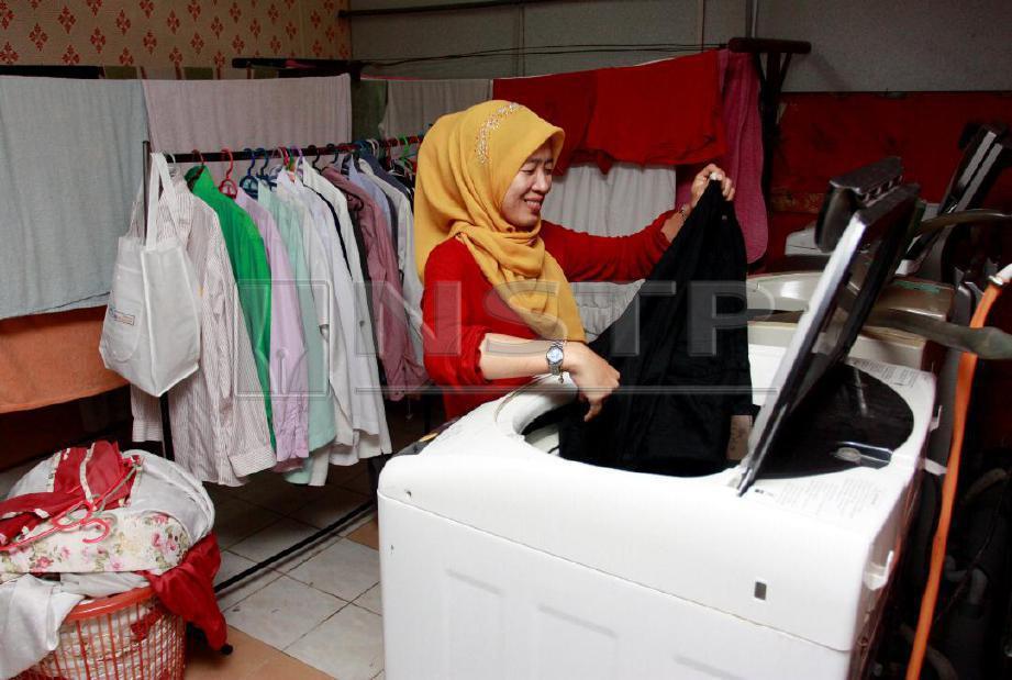 PEMILIK kedai dobi, Wan Nurul Huda Wan Ab Ghani, 32, menyiapkan pakaian yang dihantar pelanggannya untuk dicuci setiap kali tiba musim tengkujuh ketika ditemui di kedainya di Taman Jaya, Wakaf Bharu. FOTO Nik Abdullah Nik Omar