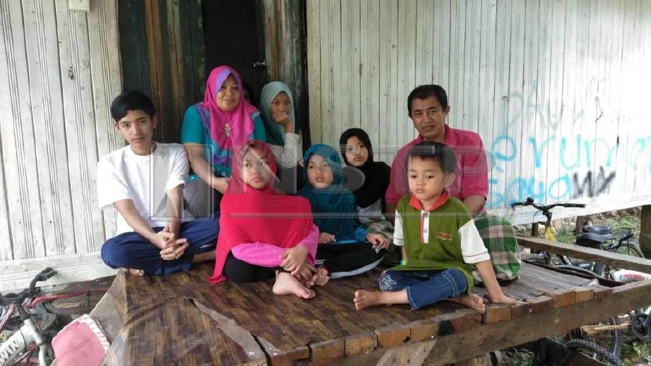 ROSLAN Zakaria, 55 (kanan) bersama  isterinya dan sebahagian 10 anaknya berada di hadapan rumah sewanya yang uzur di Kampung Chenderong Batu. FOTO Nik Abdullah Nik Omar
