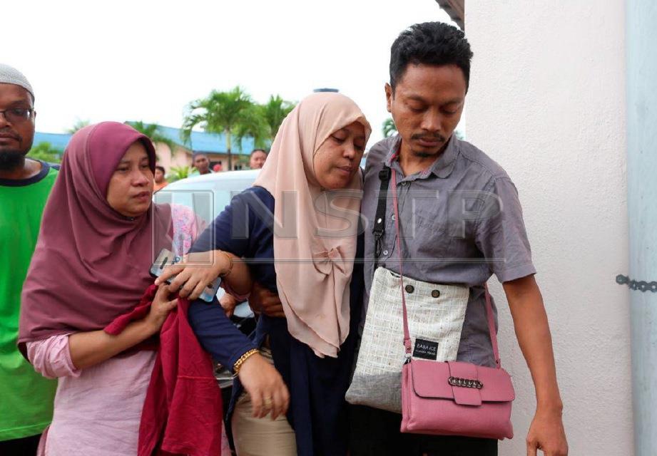 ZAWAWI Wahab, 42 membawa  isterinya Nursyahida Abdullah, 36 yang pengsan selepas melihat ketiga-tiga anak mereka yang lemas di pantai Sura Tengah di bilik forensik Hospital Dungun. FOTO Imran Makhzan