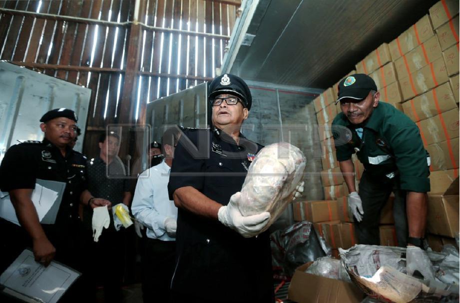 PESURUHJAYA Polis Sabah, Datuk Omar Mammah menunjukkan daging tenggiling yang beku di gudang penyimpanan di Kampung Bontoi, Tamparuli. FOTO Edmund Samunting