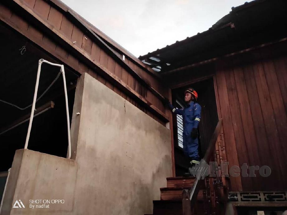 ANGGOTA APM Padang Terap melihat kerosakan pada bumbung rumah penduduk di Kampung Sungai Durian yang diterbangkan angin dalam kejadian ribut. FOTO Ihsan APM