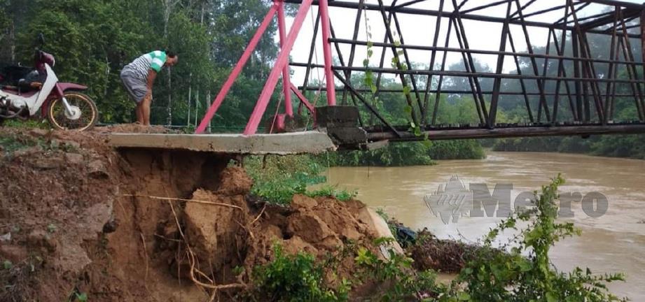 PENDUDUK meninjau keadaan tebing yang runtuh di jambatan Sungai Pedu di Kampung Tanjung Siam, Pedu. FOTO Ihsan Pembaca