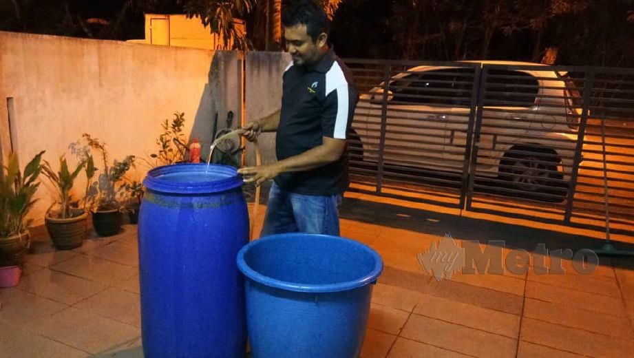 KAKITANGAN swasta, Mohd Fazli Kamarudin mengisi air lebih awal di dalam tong bagi menghadapi gangguan bekalan air. FOTO Faliq Lajim