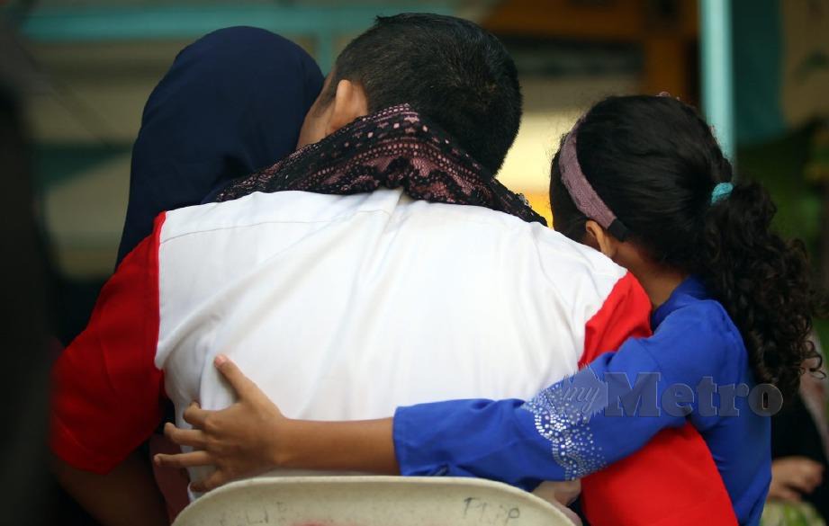 PENGHUNI banduan akhir atas kesalahan dadah, Nasir, 36, (bukan nama sebenar) dipeluk dua anak perempuannya semasa dipertemukan sempena Program Jalinan Kasih Sambutan Perayaan Hari Raya Aidilfitri di Kantin Pegawai, Penjara Reman Pulau Pinang. FOTO Danial Saad