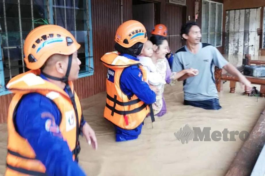 ANGGOTA APM Tawau membantu penduduk berpindah berikutan kediaman mereka terjejas akibat banjir. FOTO Ihsan APM