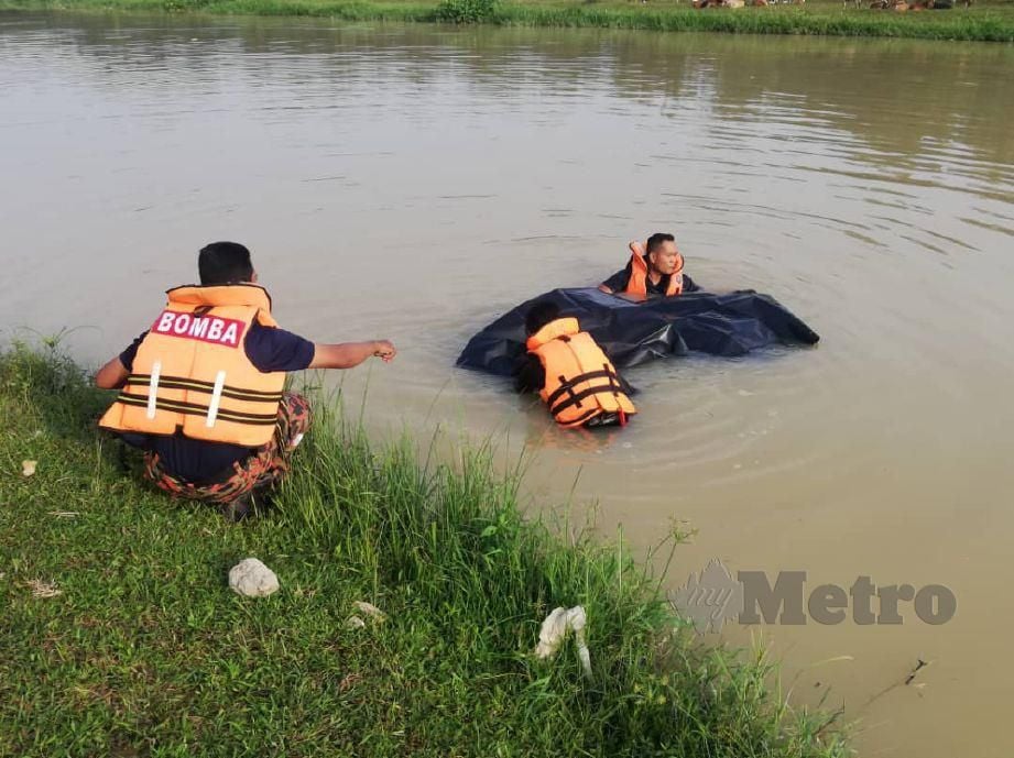 ANGGOTA bomba menaikkan mayat remaja lelaki yang terjatuh ke dalam Sungai BKE Lunas, di sini semalam. FOTO Ihsan Bomba