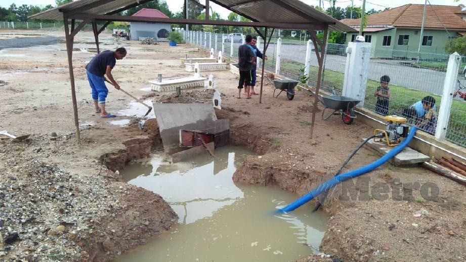 PROSES menyedut air hujan yang bertakung dalam lubang  menyebabkan hakisan pada kubur di tanah perkuburan Islam Azzahrah perkampungan Indera Sempurna. FOTO Mohd Rafi Mamat