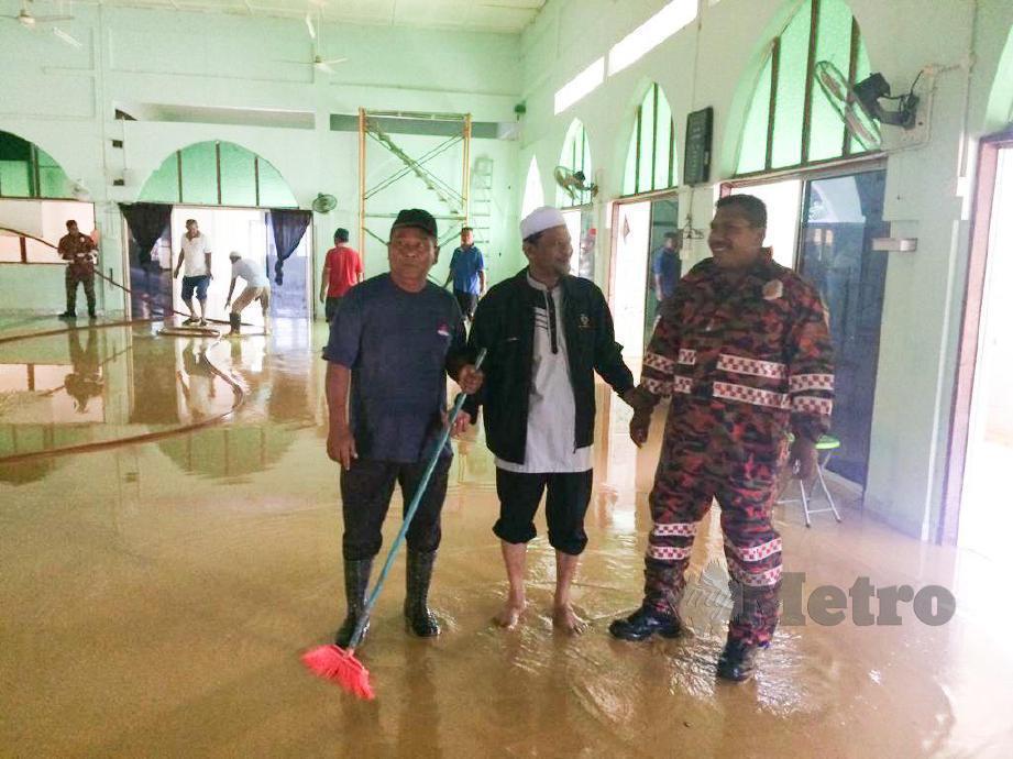 ANGGOTA Jabatan Bomba dan Penyelamat Malaysia (JBPM) bersama penduduk kampung membersihkan masjid Chenulang di Kuala Krai ketika air mulai surut selepas dilanda banjir. FOTO Ihsan Bomba