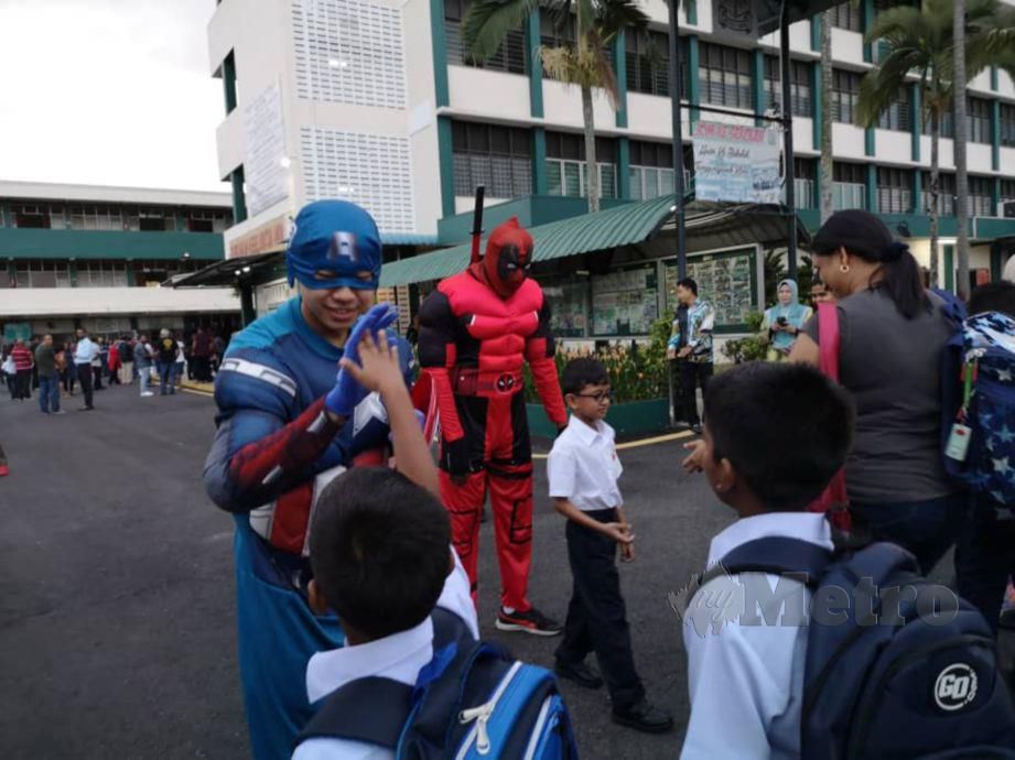 WATAK adiwira Captain Amerika dan Deapool meraikan murid hadir hari pertama sesi persekolahan di Sekolah Kebangsaan St Paul's Seremban. FOTO Hasriyasyah Sabudin