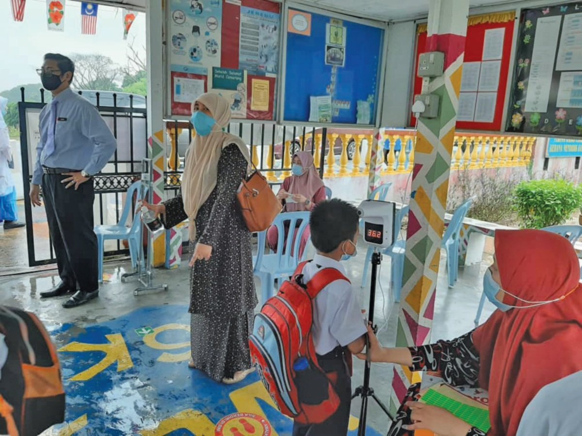 MURID sekolah Kebangsaan Bandar Baru Bangi memeriksa suhu badan sambil dibimbing guru bertugas.