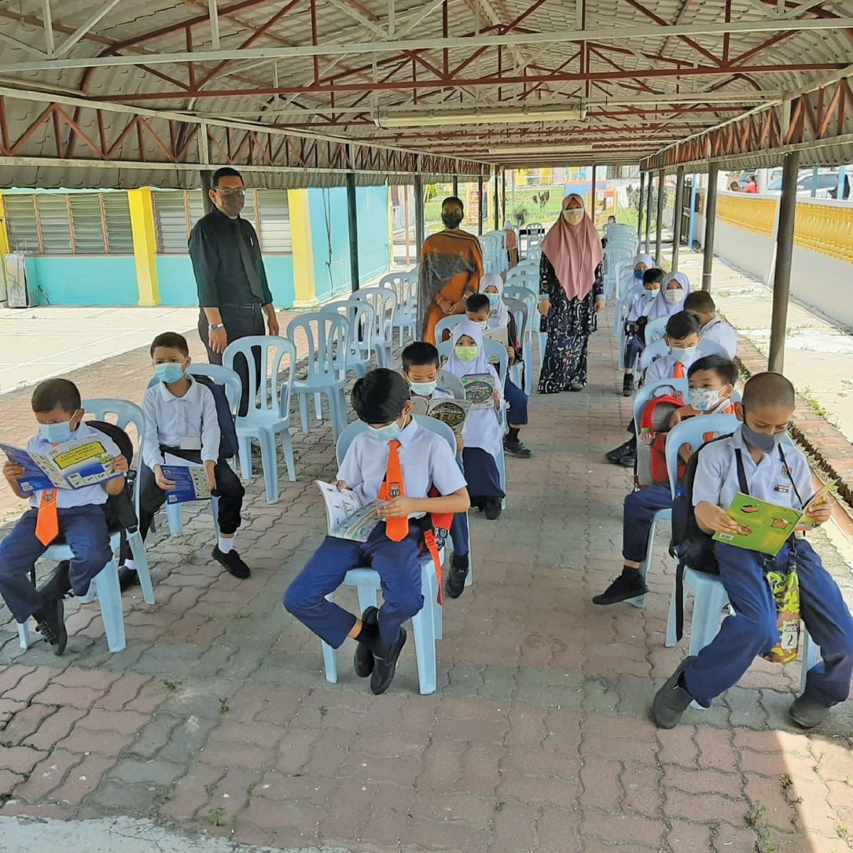 MURID Sekolah Kebangsaan Bandar Baru Bangi  sempat membaca buku sementara menunggu giliran untuk pemeriksaan suhu badan.
